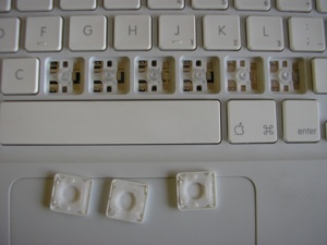 Partial pic of MacBook keyboard, keycap holes, and keycaps with scissor mechanisms